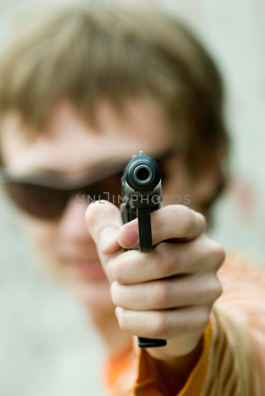 Man pointing a hand gun right at the viewer. Shallow depth of field used with focus on the barrel.