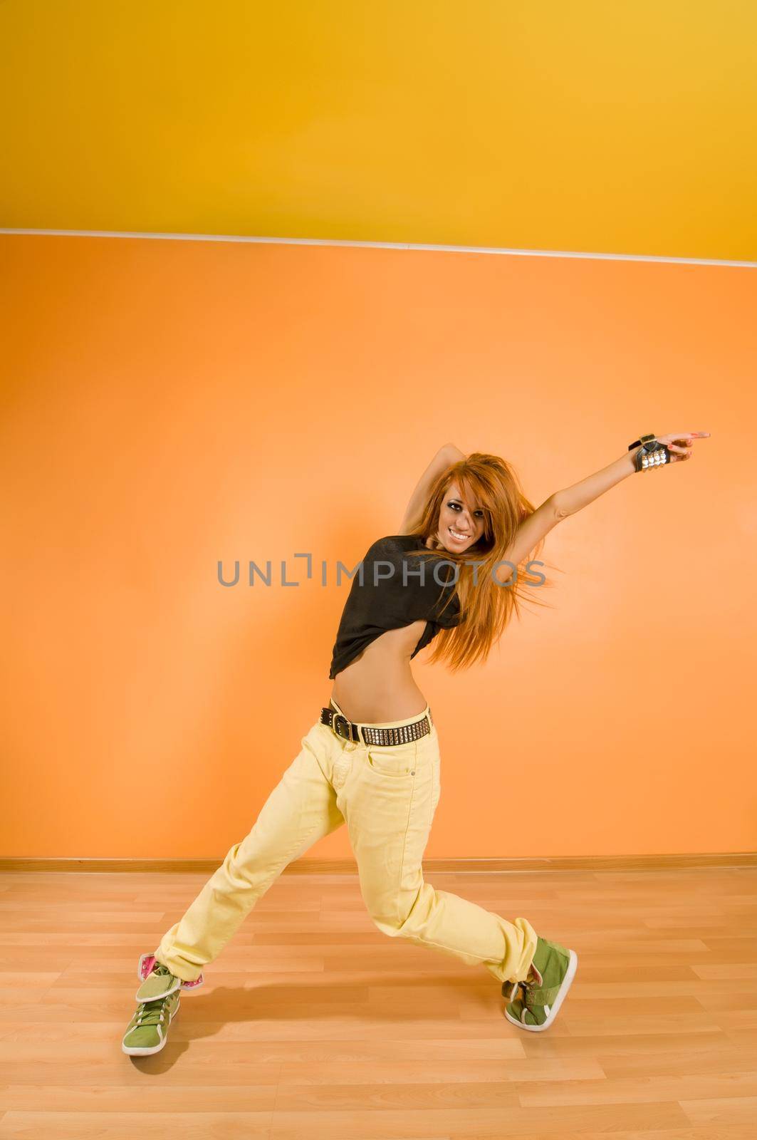 Red hair girl dancing hip-hop over vivid background
