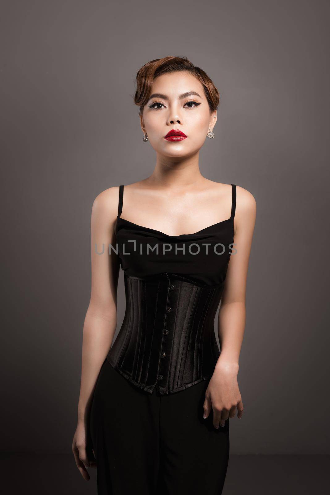 Sexy attractive asian woman posing in fashionable black dress over grey background by makidotvn