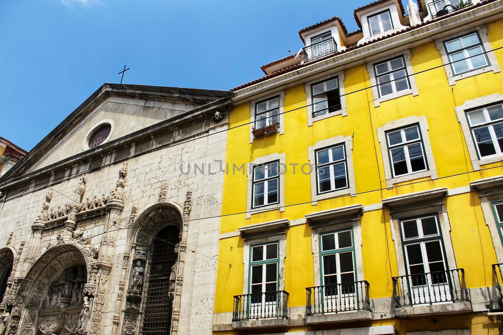 Nossa Senhora da Conceicao church facade next to Colorful and majestic old houses in Lisbon. Old stone facades with big windows in Spring.