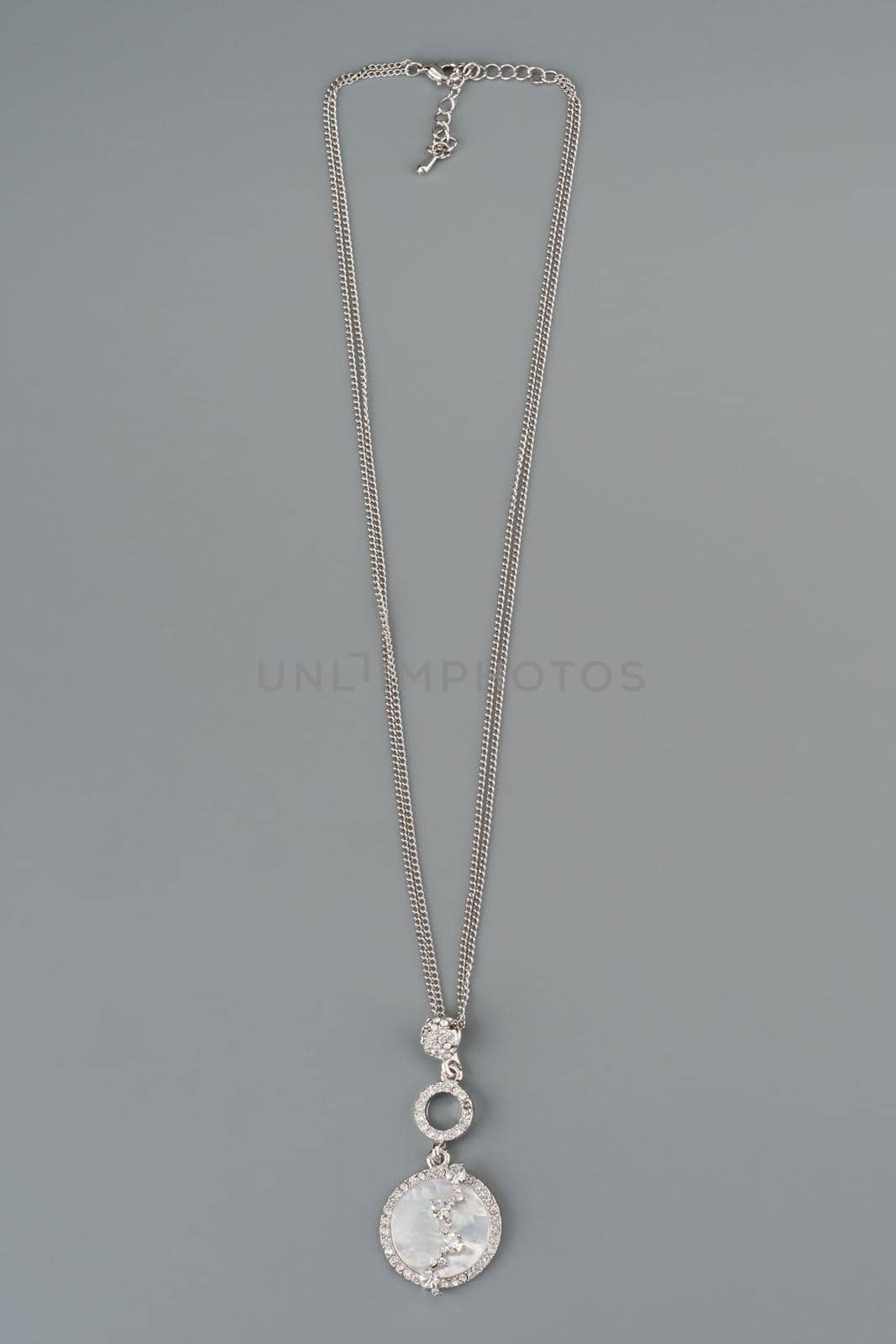 Silver necklace with pendant shot on gray background