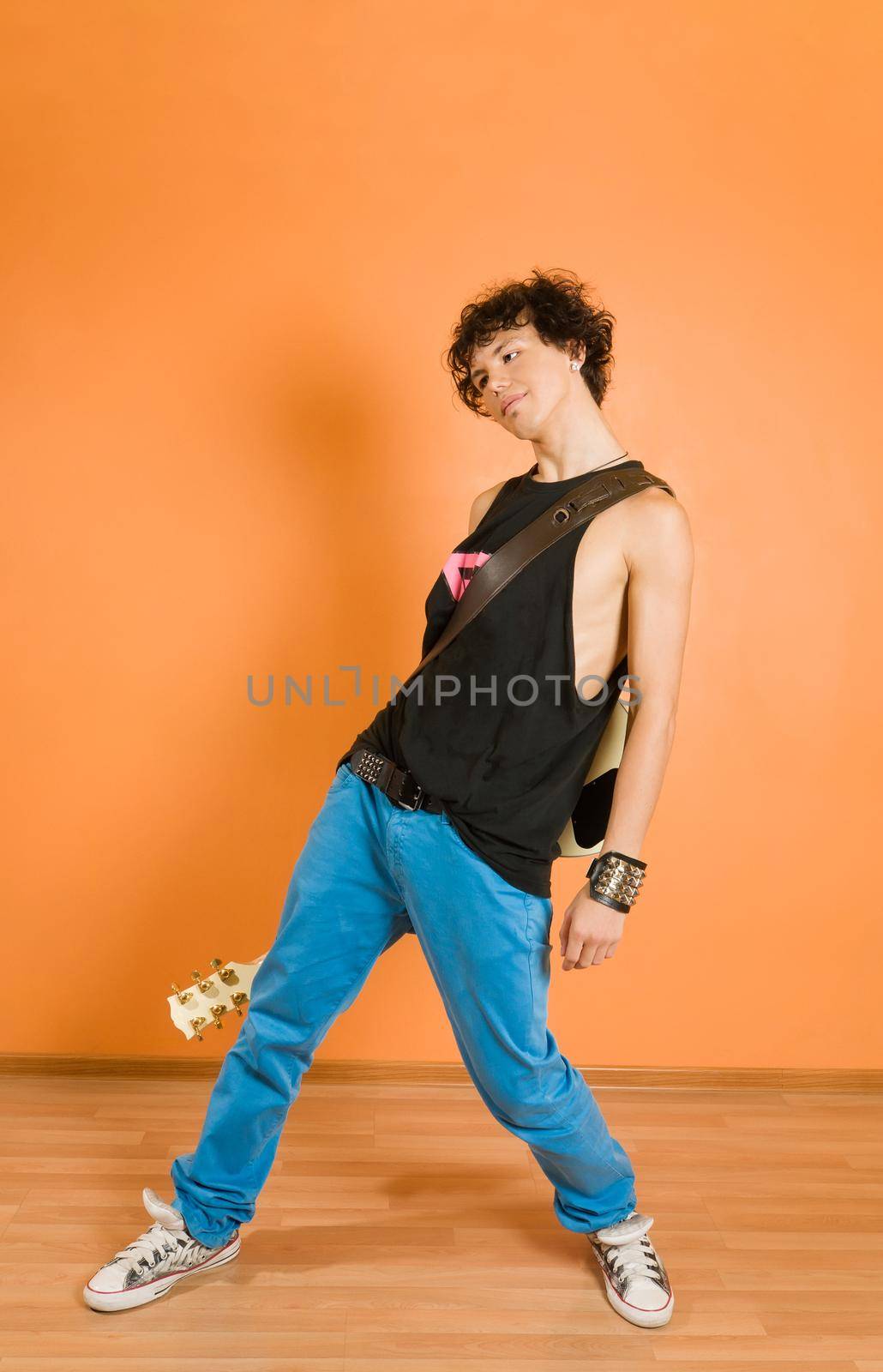 Young performer posing with guitar at the vivid background