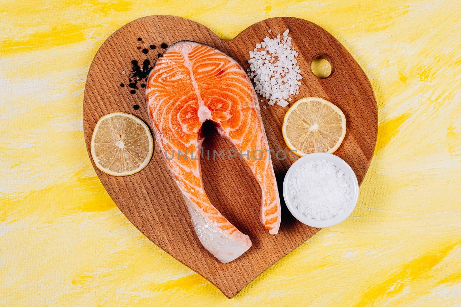 Fresh raw salmon red fish with spices, lemon, pepper on yellow stone background. Top view, flat lay by darksoul72