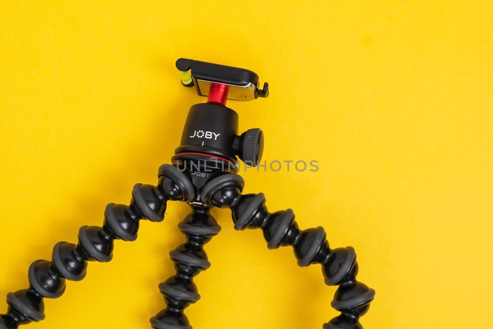 Tyumen, Russia-June 21, 2021: Flexible tripod Joby. Equipment for recording movies on a yellow background. by darksoul72