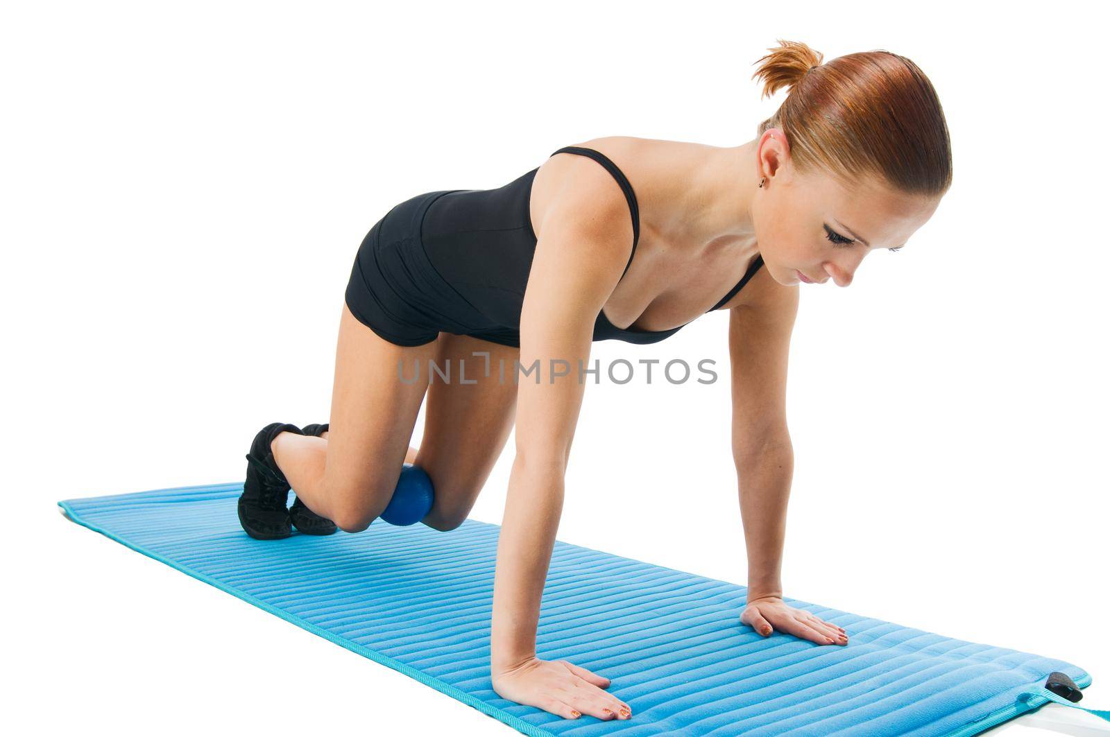 Beautiful fit red girl practicing pilates or callanetics with ball and blue yoga mat