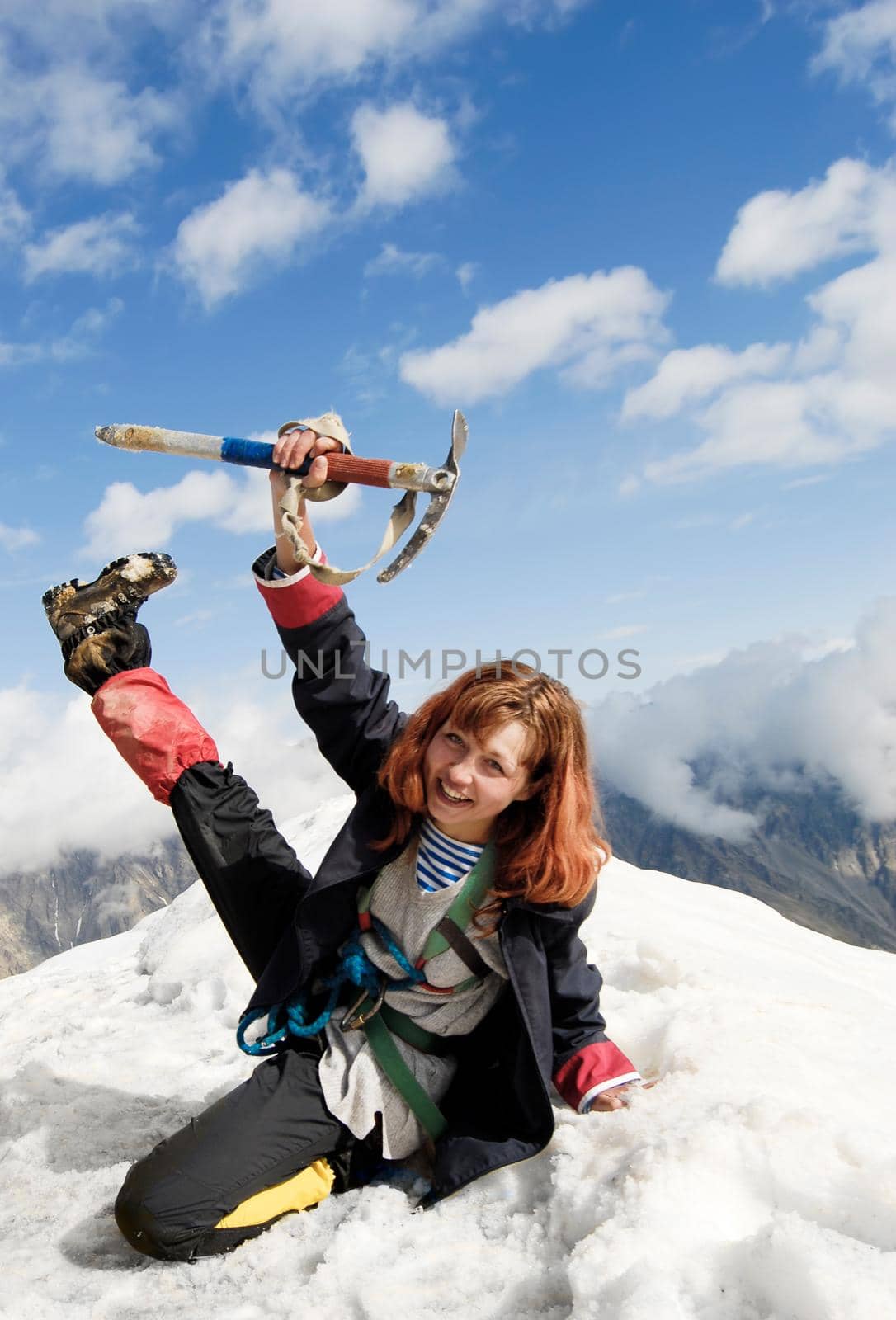 Red-haired mountaineer girl cheering at the top of a high mountain!