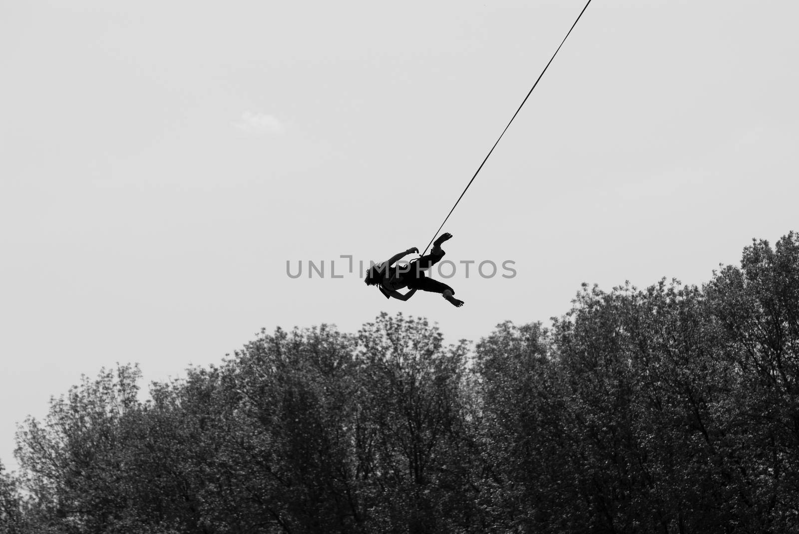 Silhouette of a girl jumping with a rope from the bridge