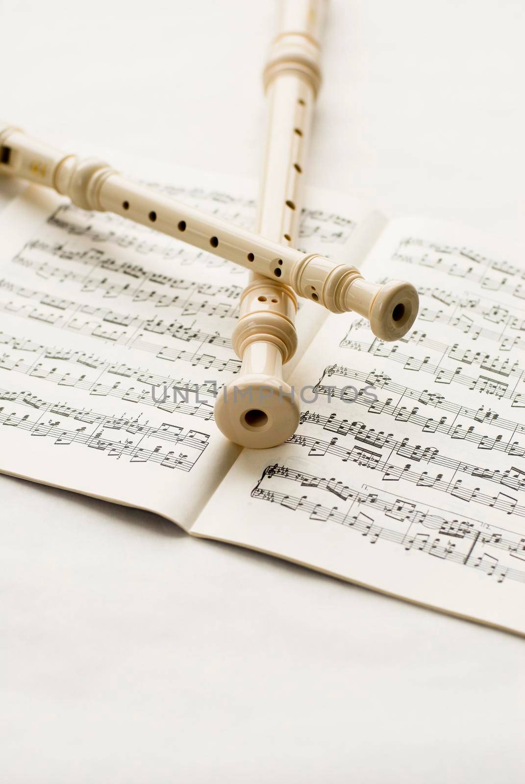 Two block-flutes placed over textbook with musical notes. High key