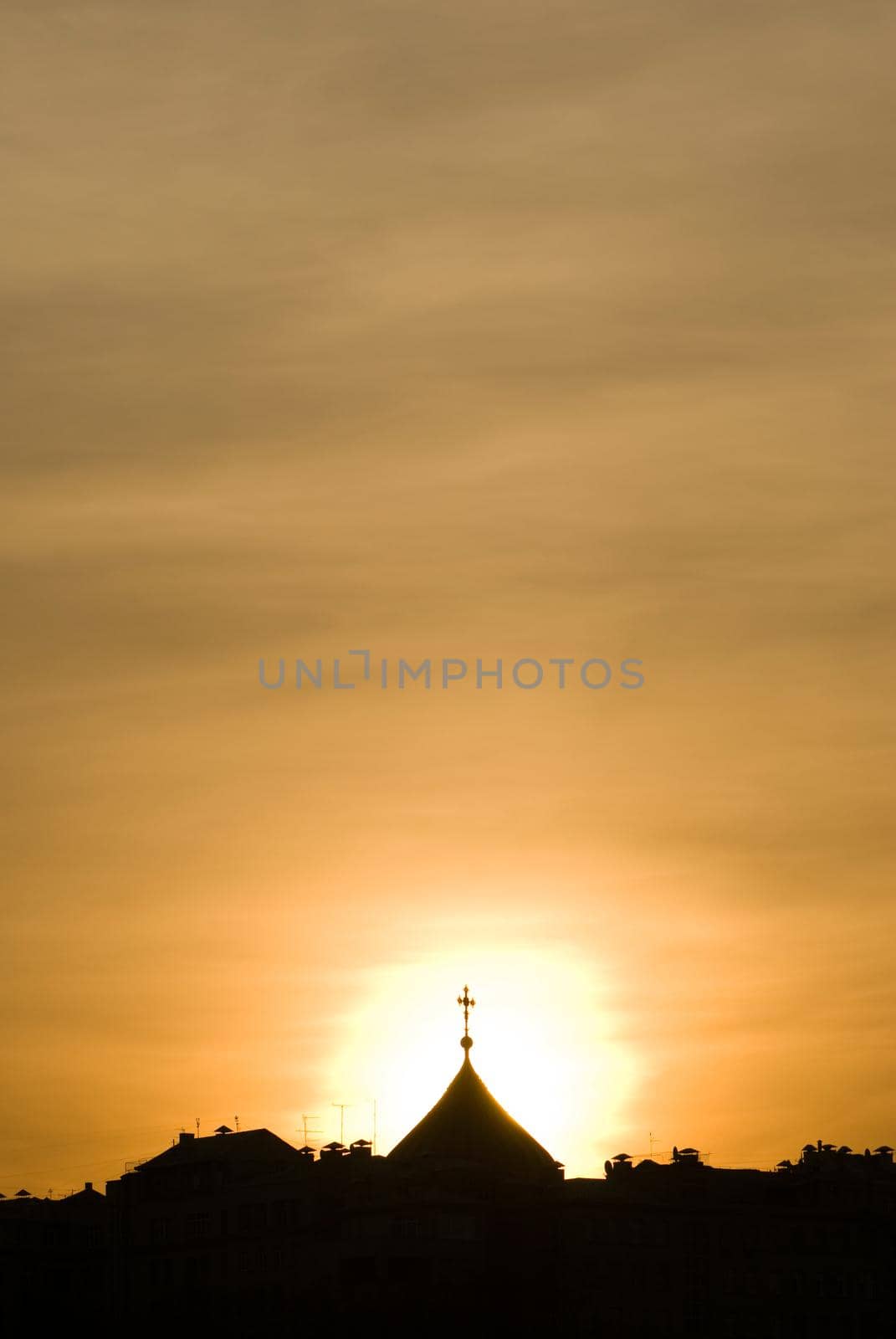 Church dome is backlit with a sunset sky