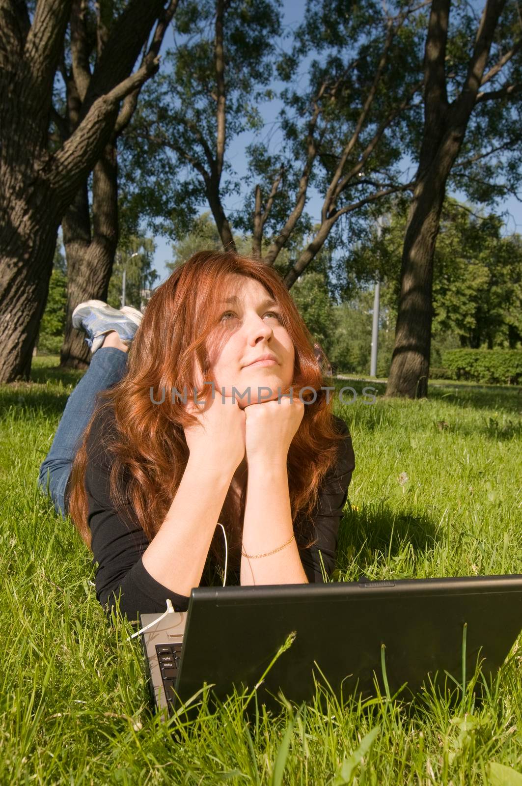 Beautiful girl listening to the music from her laptop in the park.