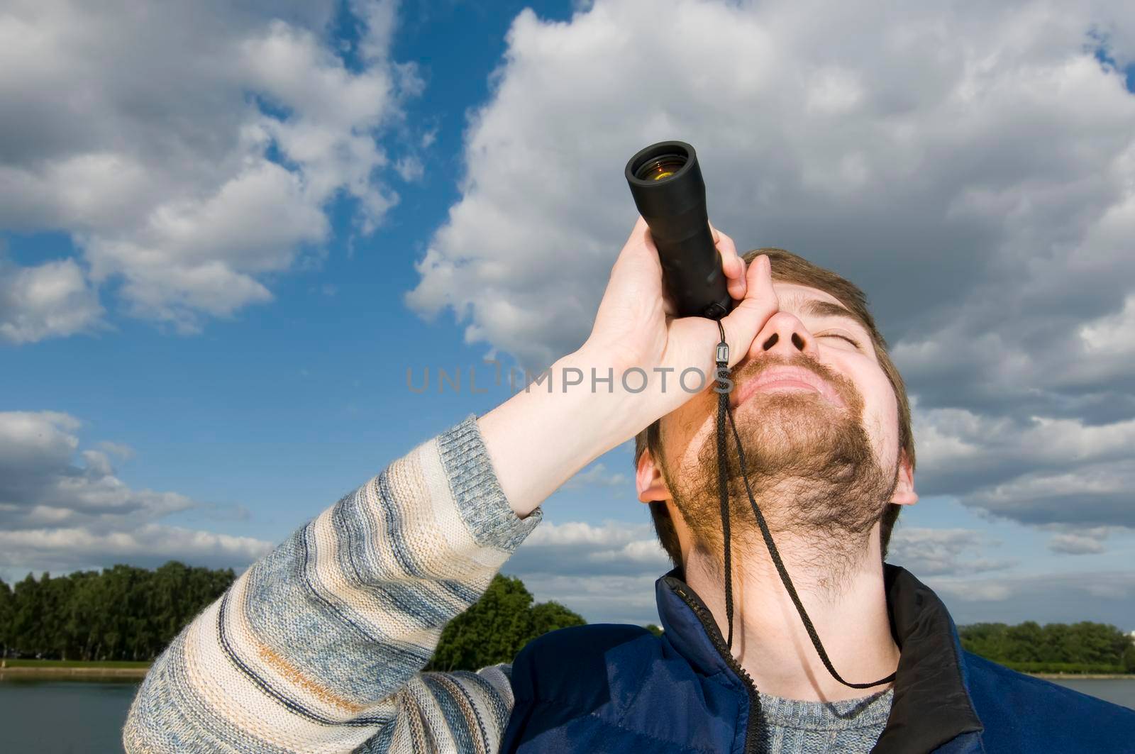 Young man hangs out in a park looking up with his spyglass.