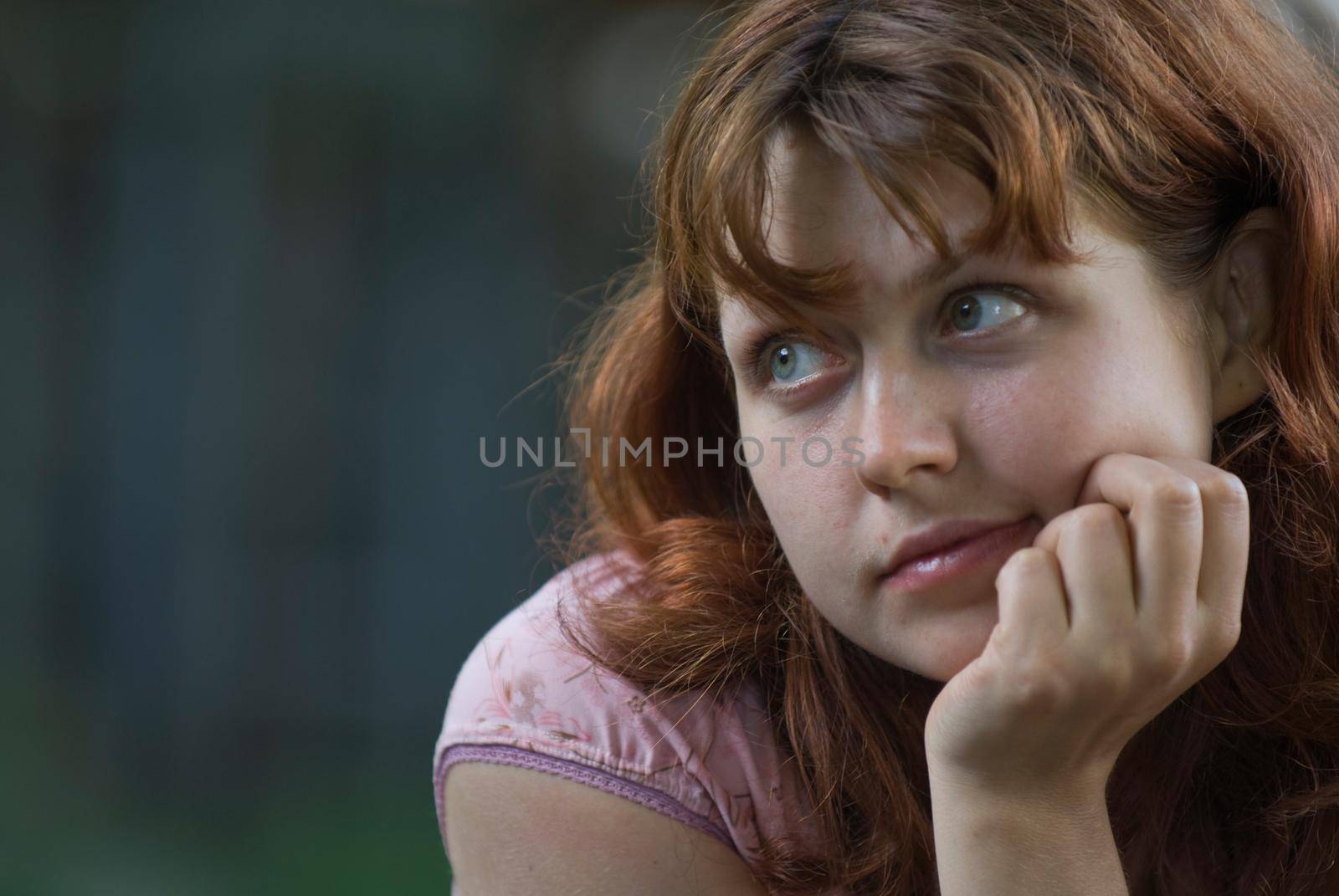 Portrait of a red-haired girl in a dreamy mood