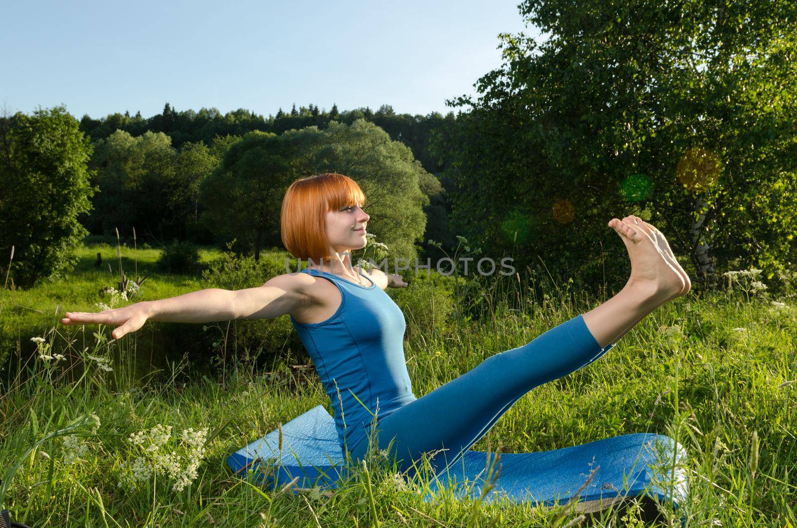 Red woman practicing fitness yoga outdoors by nikitabuida
