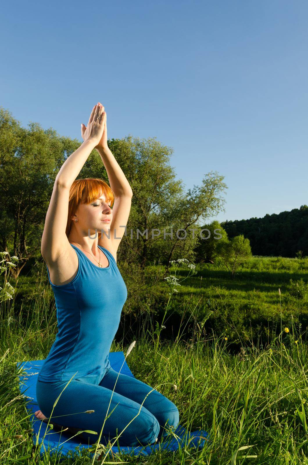 Red woman practicing fitness yoga outdoors by nikitabuida