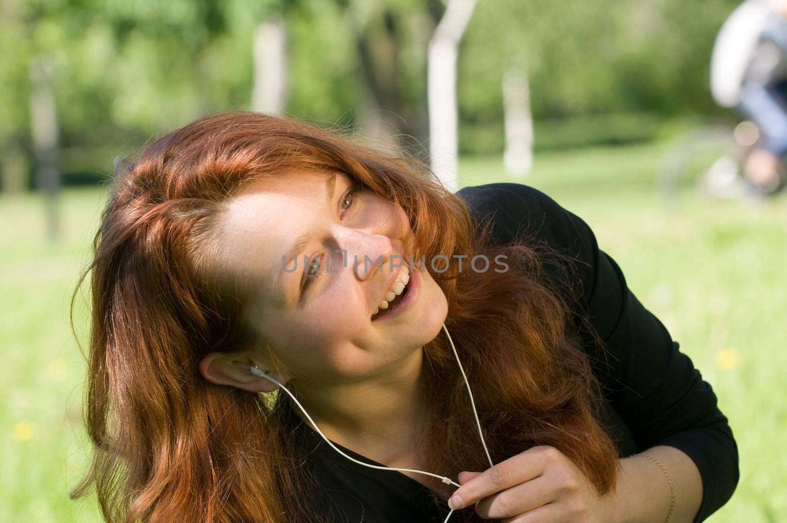 Red haired girl enjoying the music in the park