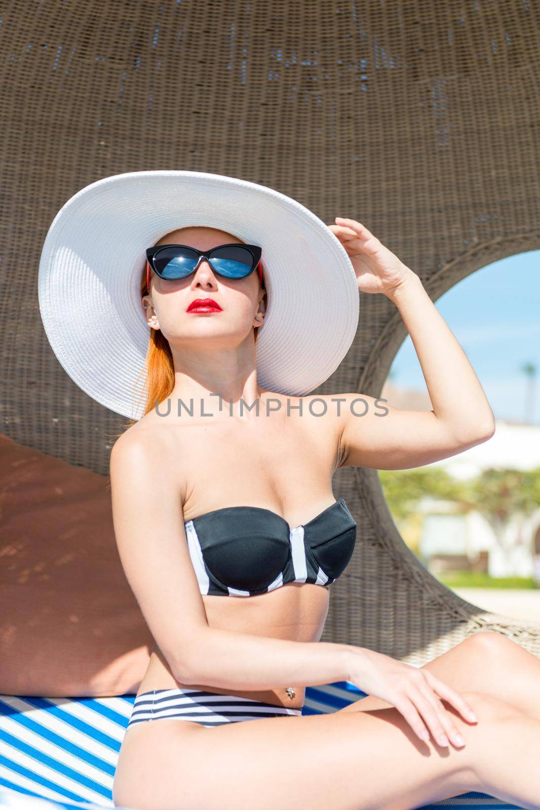 Beautiful sexy woman near pool wearing striped bikini enjoying vacation