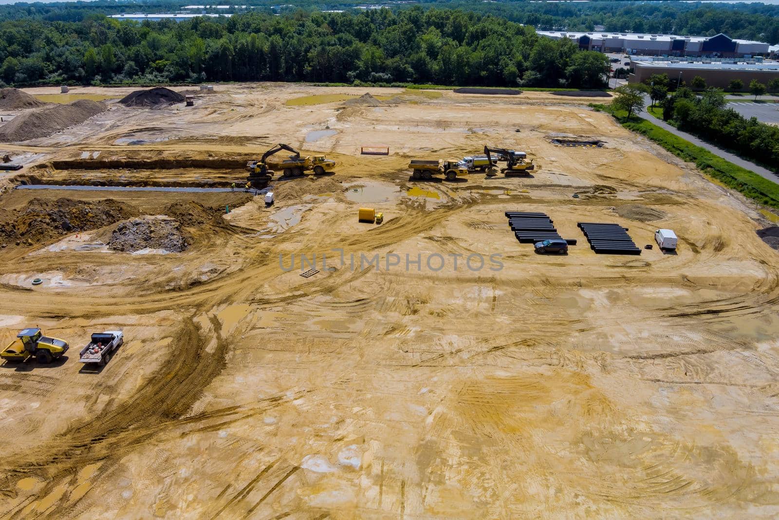 View of a large construction site where earthmoving equipment the ground to laying underground lay pipes residential buildings.