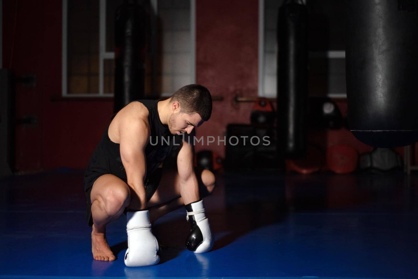 Kickboxing fighter in boxing gloves standing on knees. High quality photo