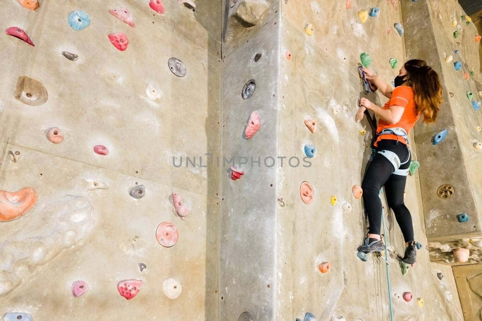 Young fit woman climbing on indoor rock wall. by HERRAEZ