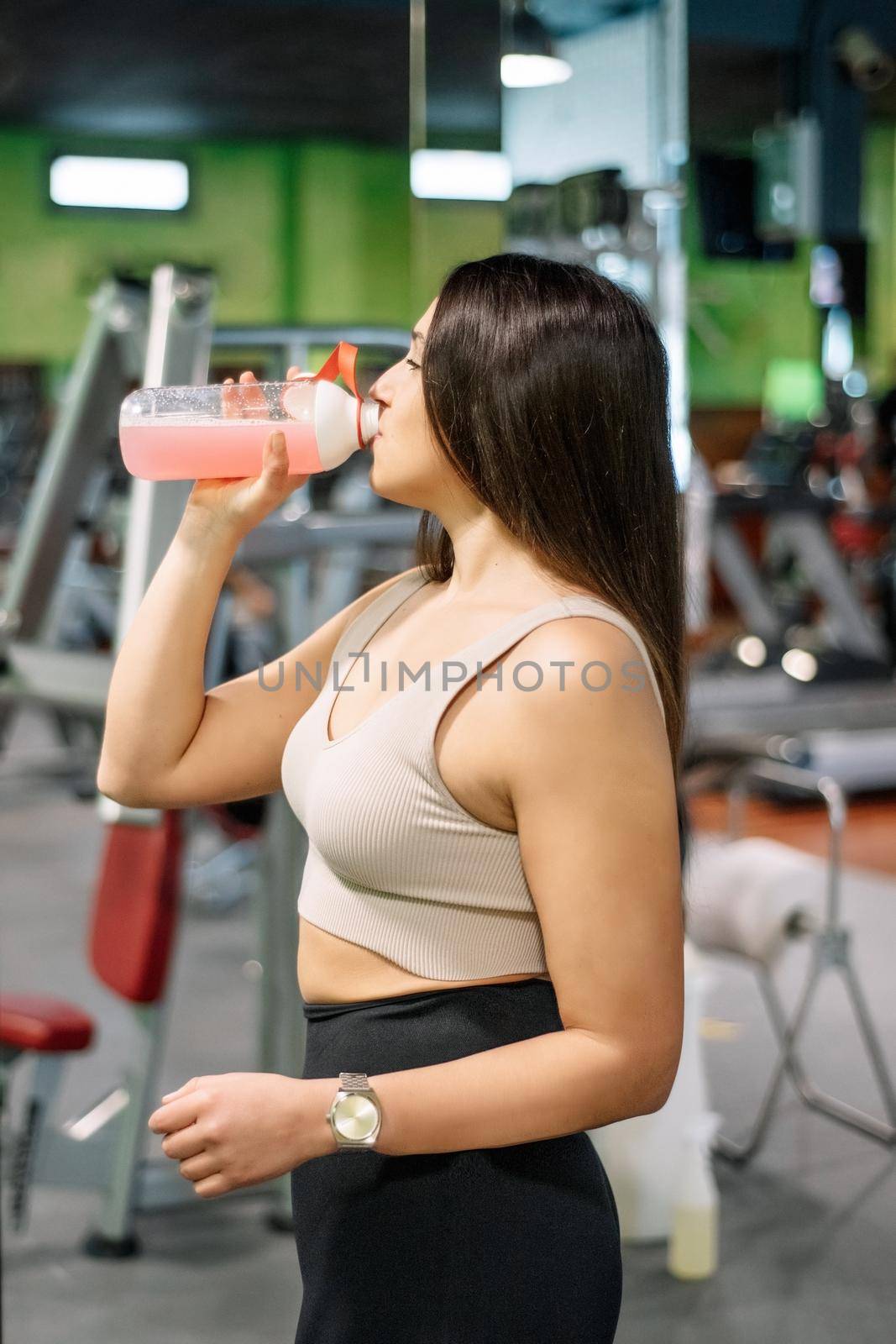 Beautiful young woman resting and drinking water in the gym. High quality photo