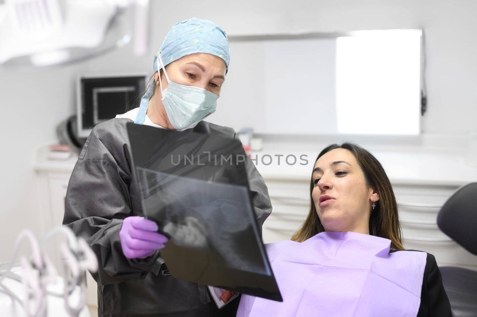 Female dentist pointing at patient's X-ray image in dental office. High quality photo