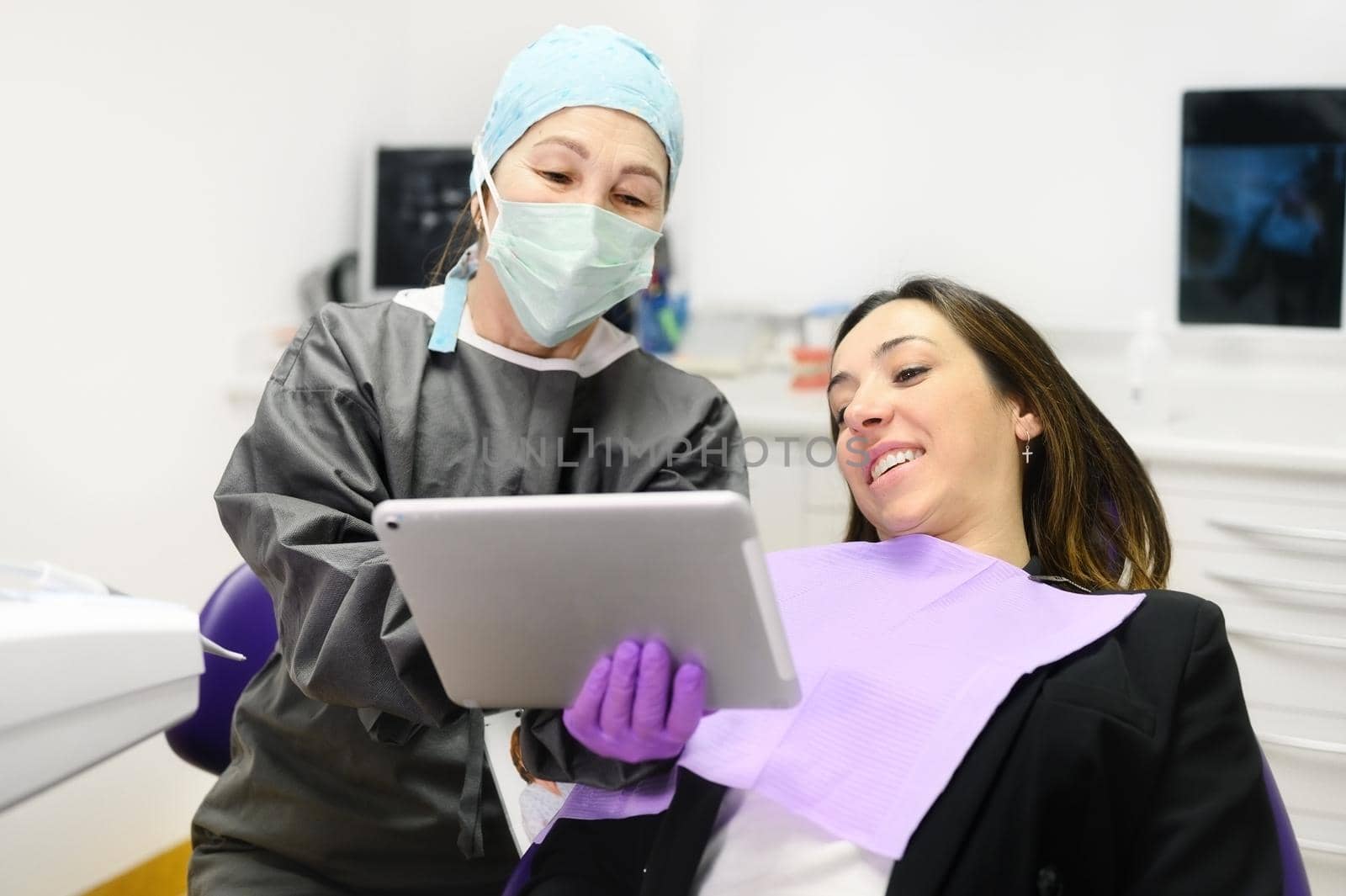 Health care concept - Female dentist showing tablet computer to woman patient at dental clinic office. High quality photo