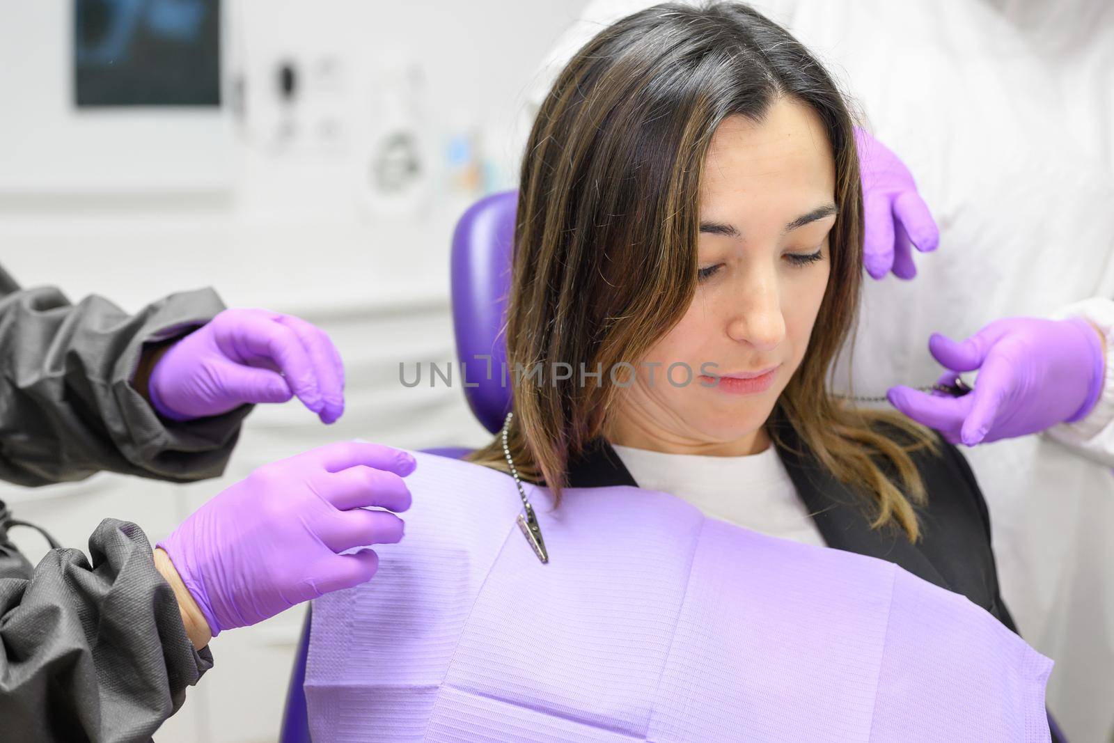 Medical secretary preparing dental treatment putting on dental bib on patient. High quality photo