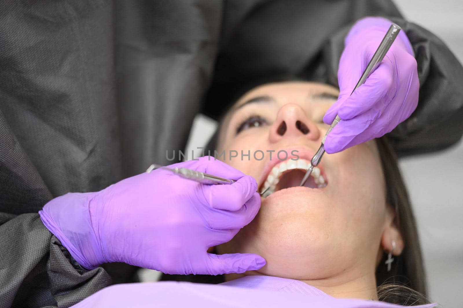 Dentist hygienist making oral hygienic cleaning in dentistry for young woman. Using professional electrical equipment dental drill machine to brush teeth in dentistry. by HERRAEZ