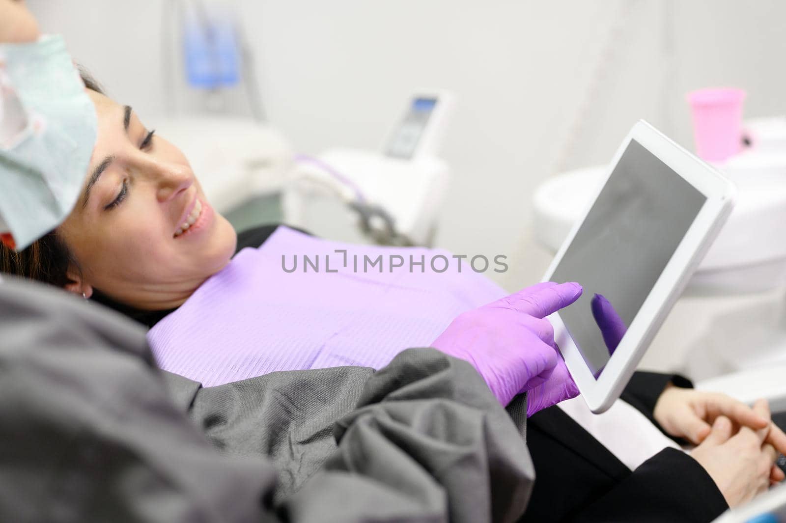Health care concept - Female dentist showing tablet computer to woman patient at dental clinic office. High quality photo