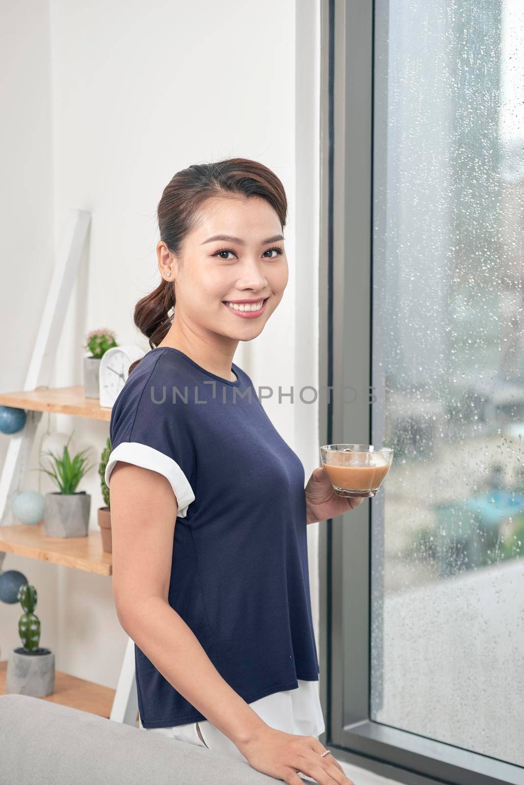 Attractive mixed female lifestyle enjoying a cup of tea looking out the window