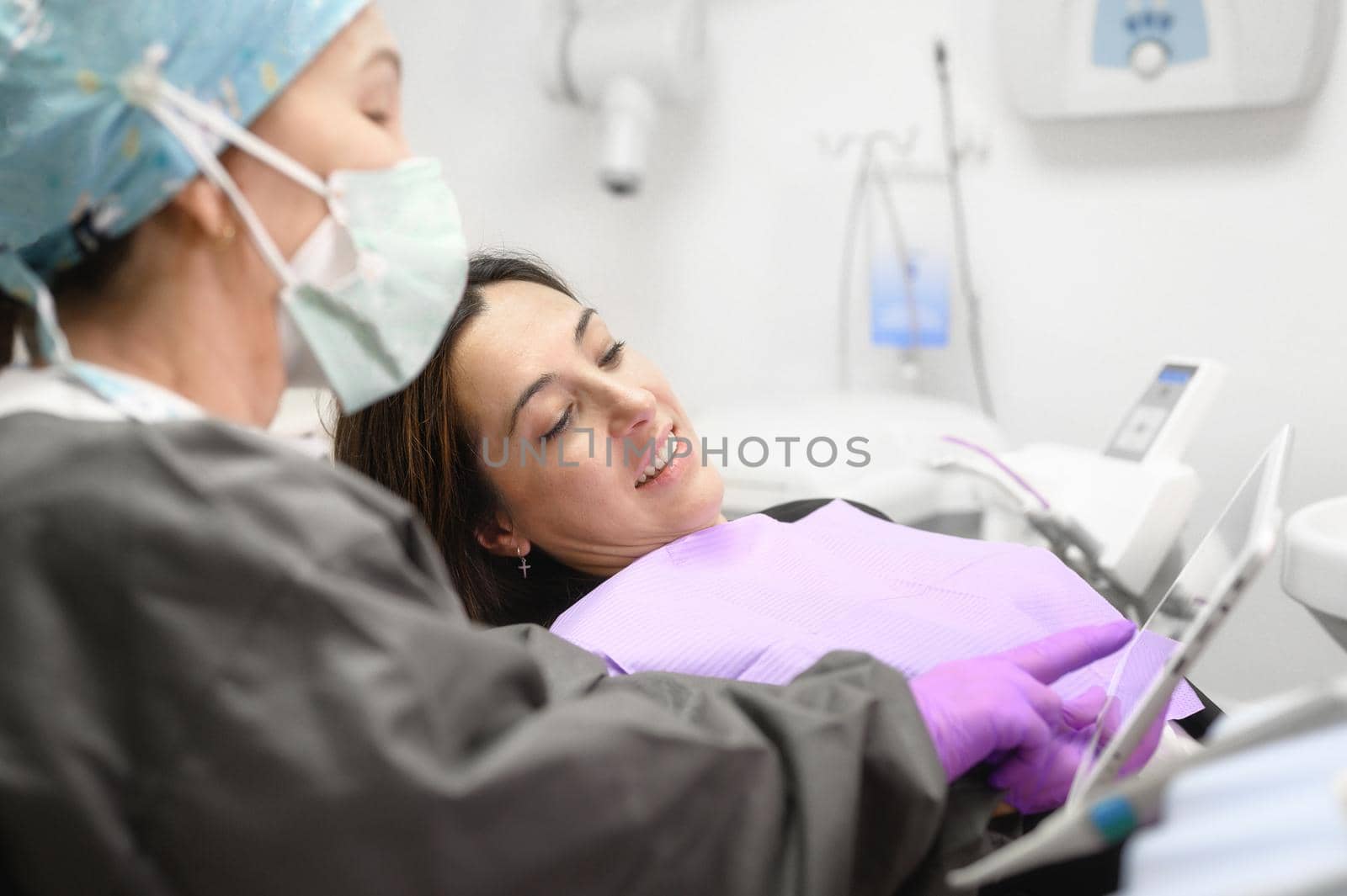 Health care concept - Female dentist showing tablet computer to woman patient at dental clinic office. High quality photo