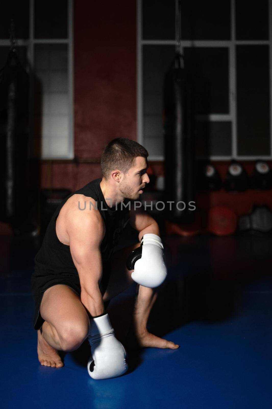 Kickboxing fighter in boxing gloves standing on knees. High quality photo