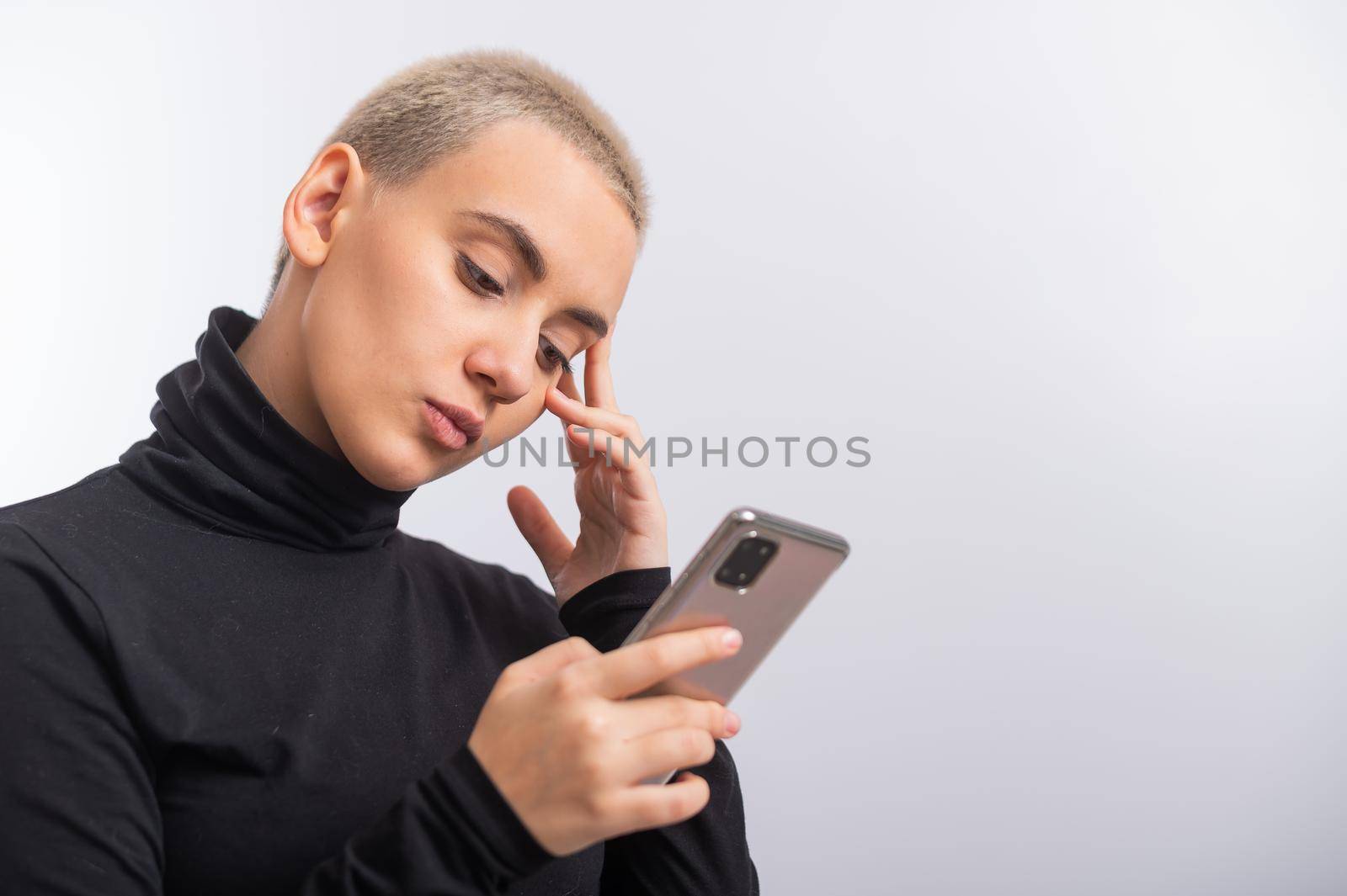 Young caucasian woman with short hair uses a smartphone on a white background