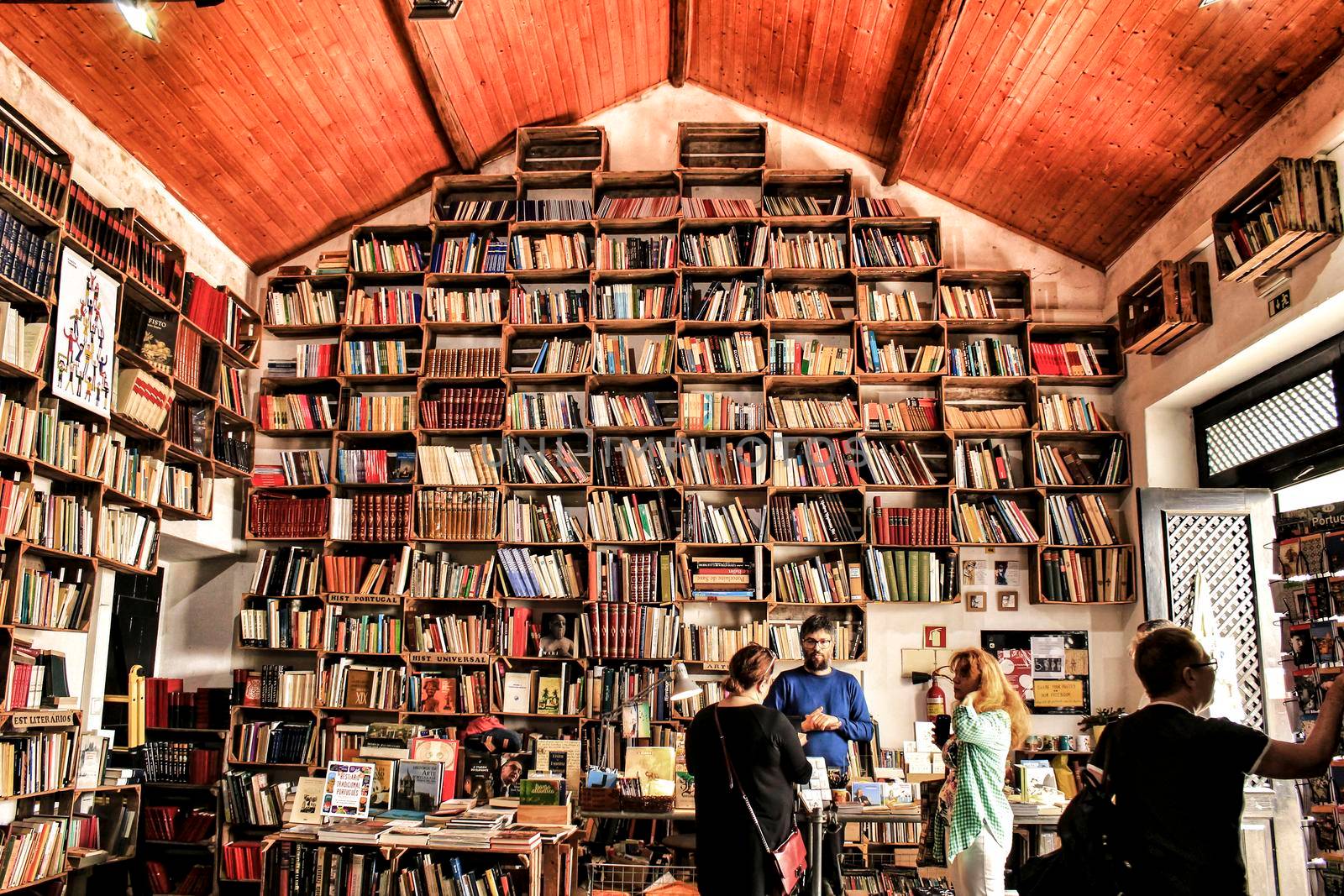 Obidos, Lisbon, Portugal- June 3, 2018: People buying books in an Old bookstore with selves full of books in Obidos, Portugal.