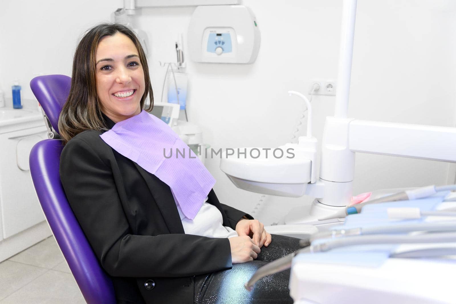 Portrait of smiling young woman lying in dental chair and looking at camera, copy space. High quality photo