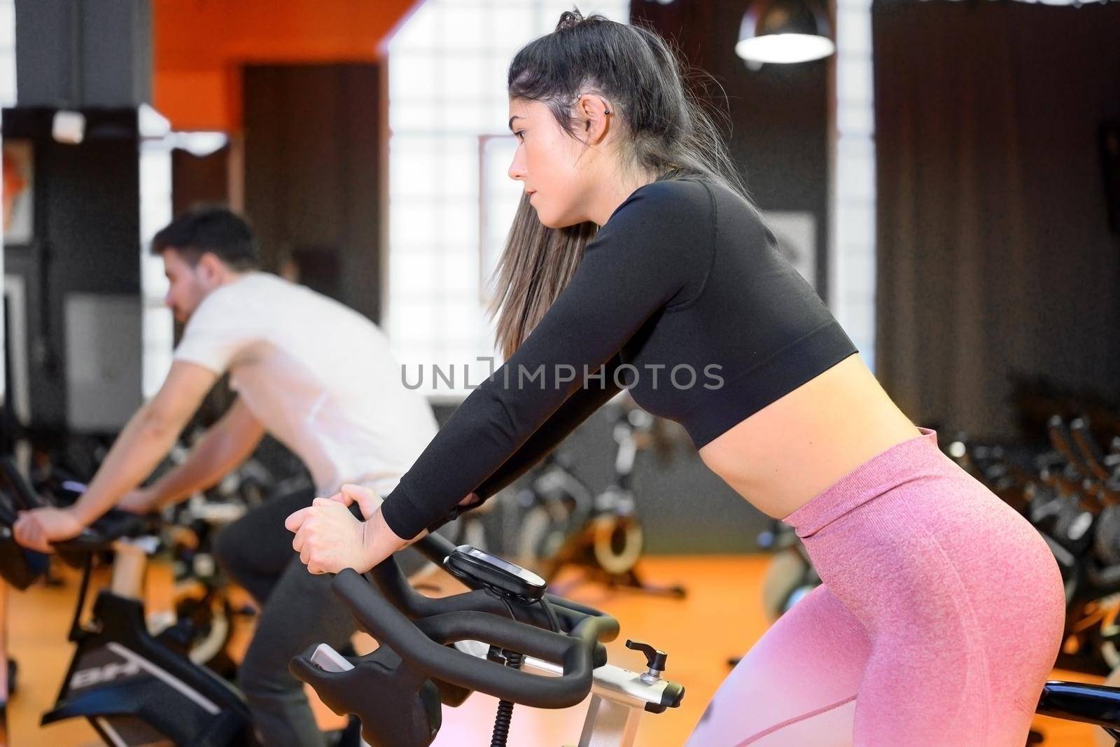 Beautiful woman cycling on a modern fitness bicycle during group spinning class at the gym. High quality photo