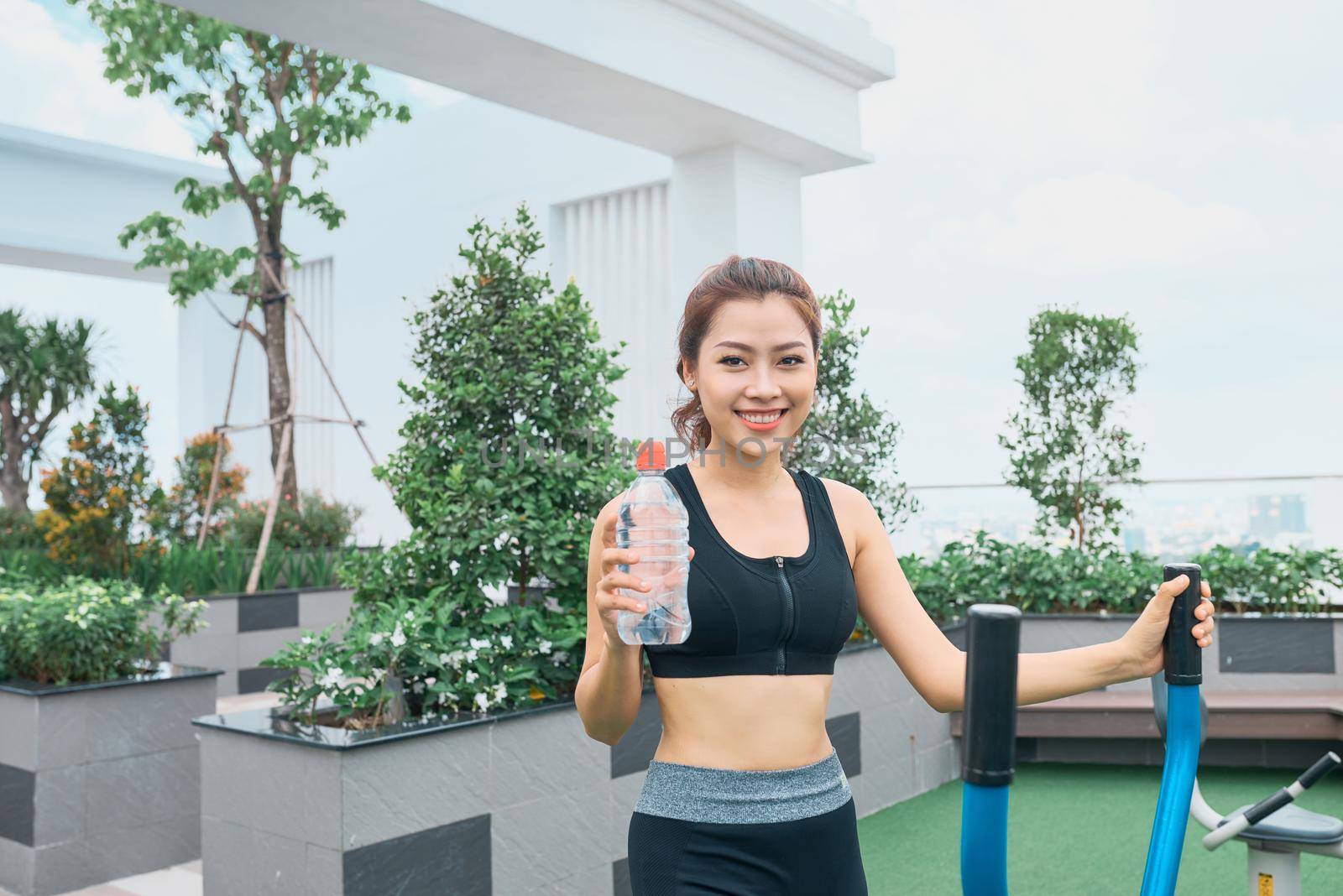 Asian woman exercising at outdoors holding water bottle by makidotvn