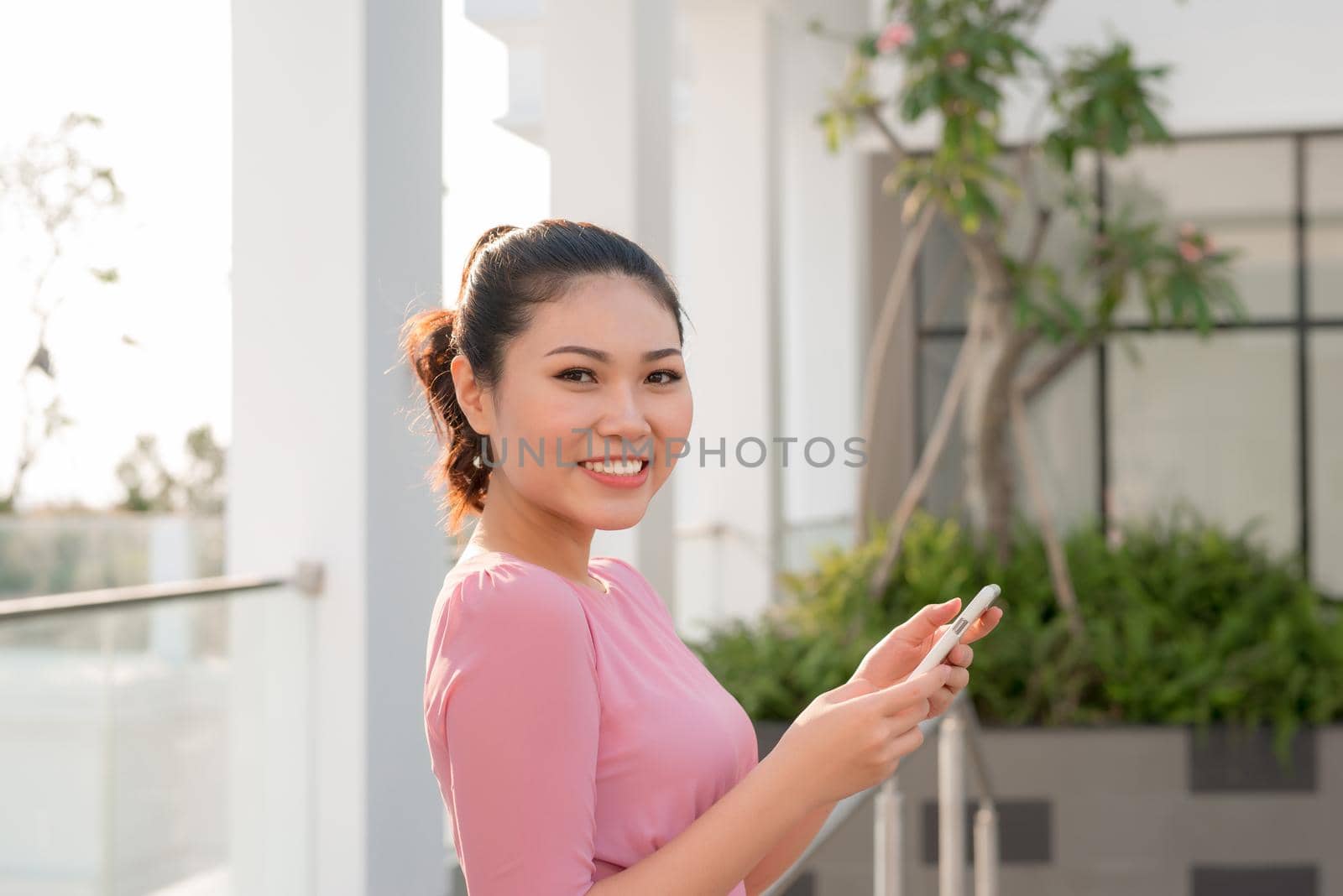 Happy beautiful woman using smart phone outdoors by makidotvn