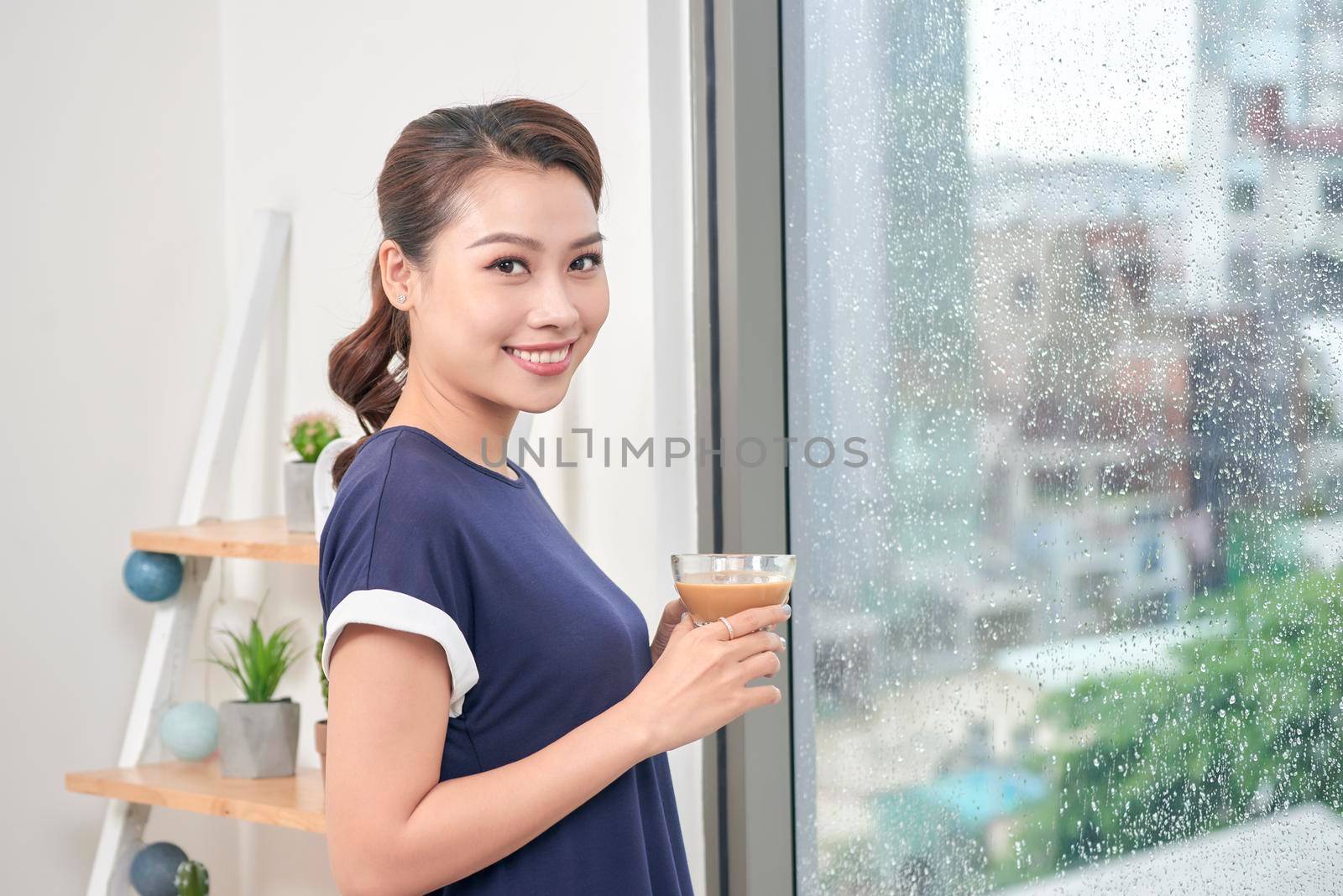 Attractive mixed female lifestyle enjoying a cup of tea looking out the window by makidotvn