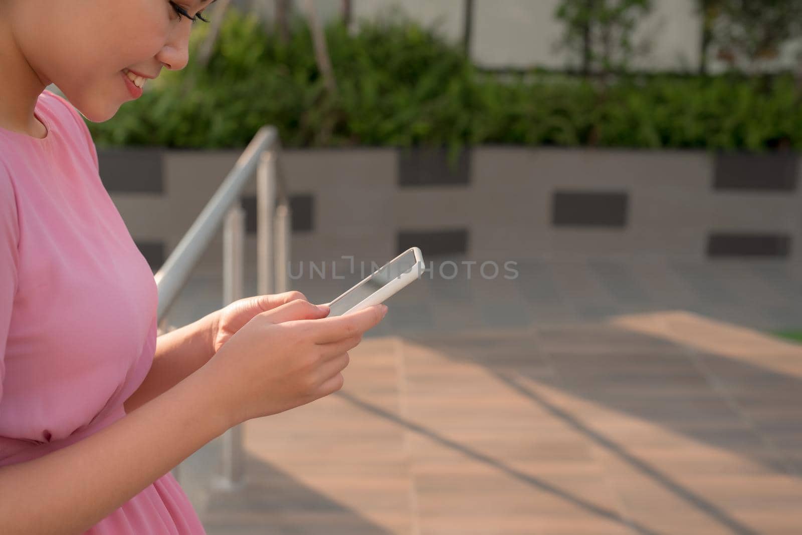 Happy beautiful woman using smart phone outdoors by makidotvn