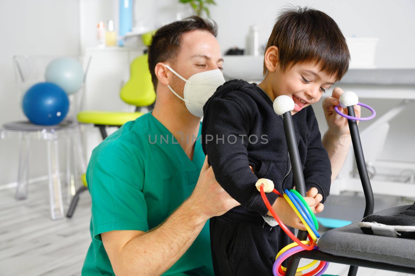 Child with cerebral palsy on physiotherapy in a children therapy center. Boy with disability doing exercises with physiotherapists in rehabitation centre. by HERRAEZ