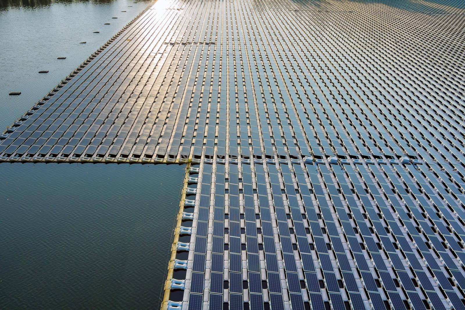 Aerial view of lake in renewable alternative electricity on floating solar panels platform by ungvar