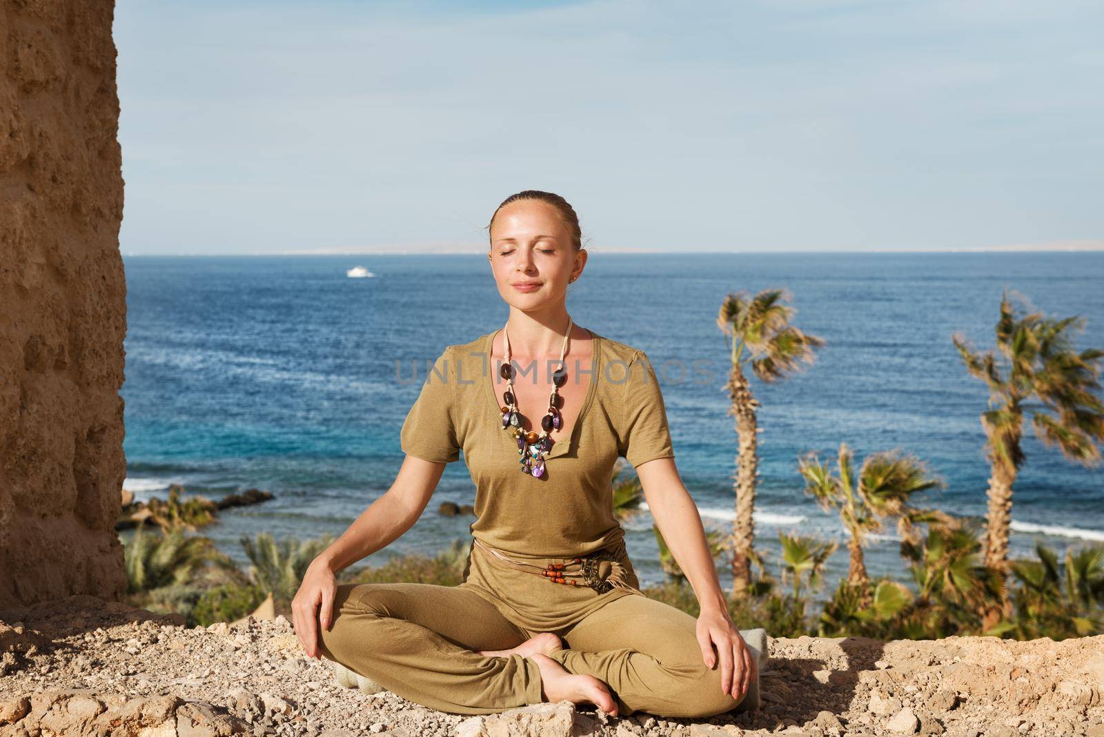 Young woman meditating in yoga asana near sea