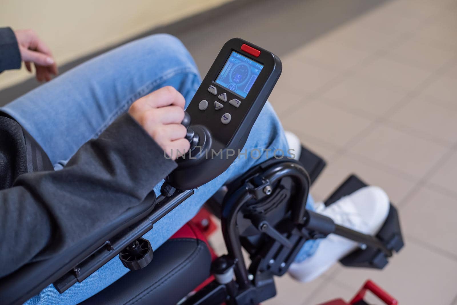 Close-up of a female hand on the control handle of an electric wheelchair.