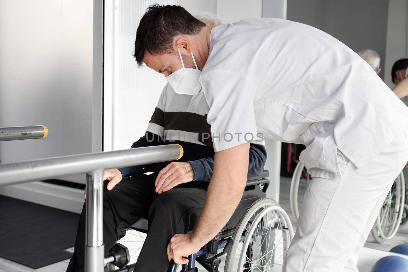 Senior Man Being Assisted By Physiotherapist In Rehab Center. by HERRAEZ