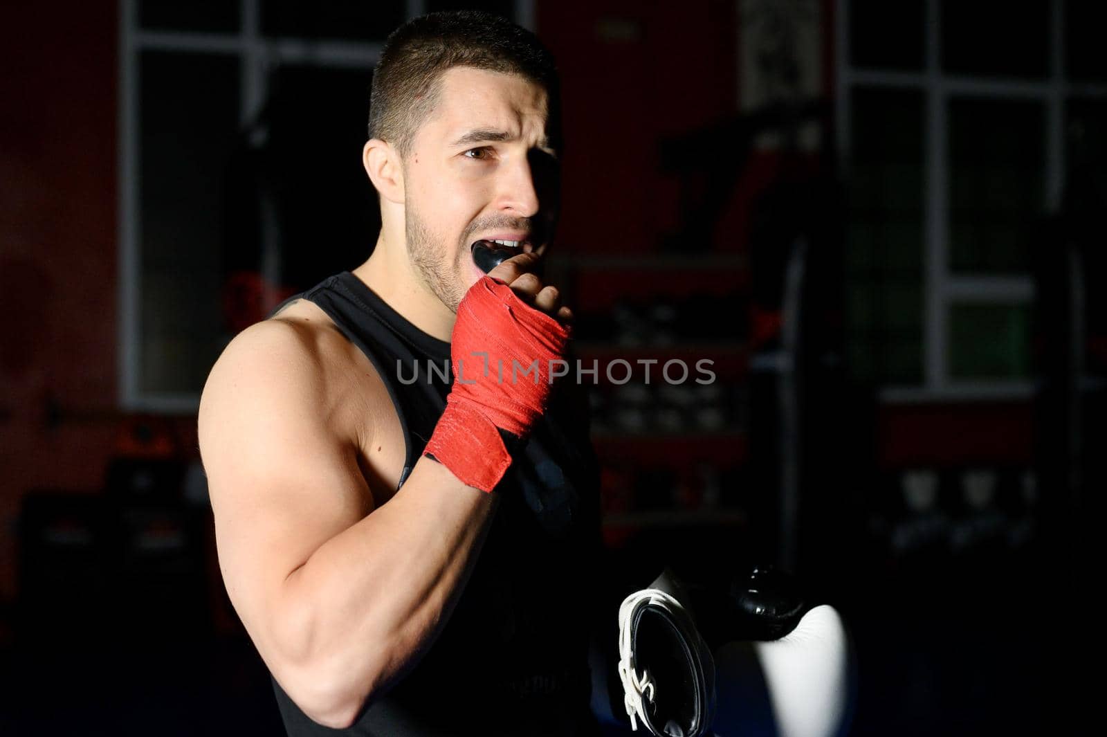 Boxing fighter putting on mouthguard. by HERRAEZ