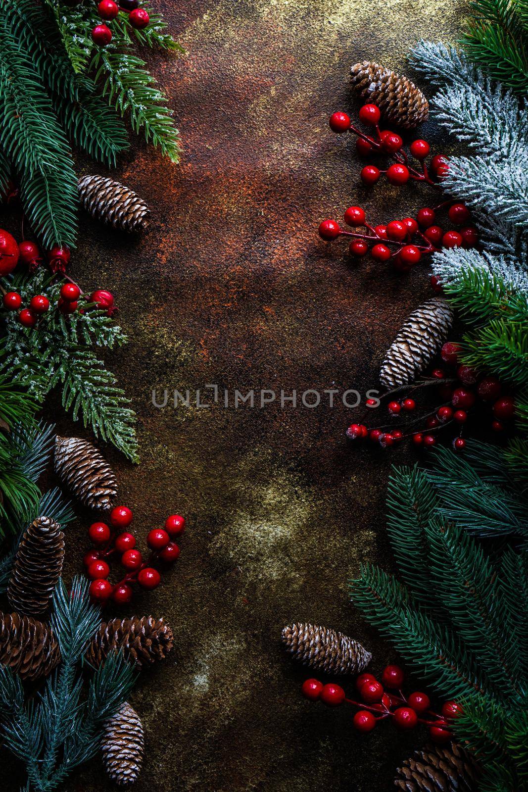 Christmas card concept with frame made with green fir branches, red decoration balls and berries on concrete background