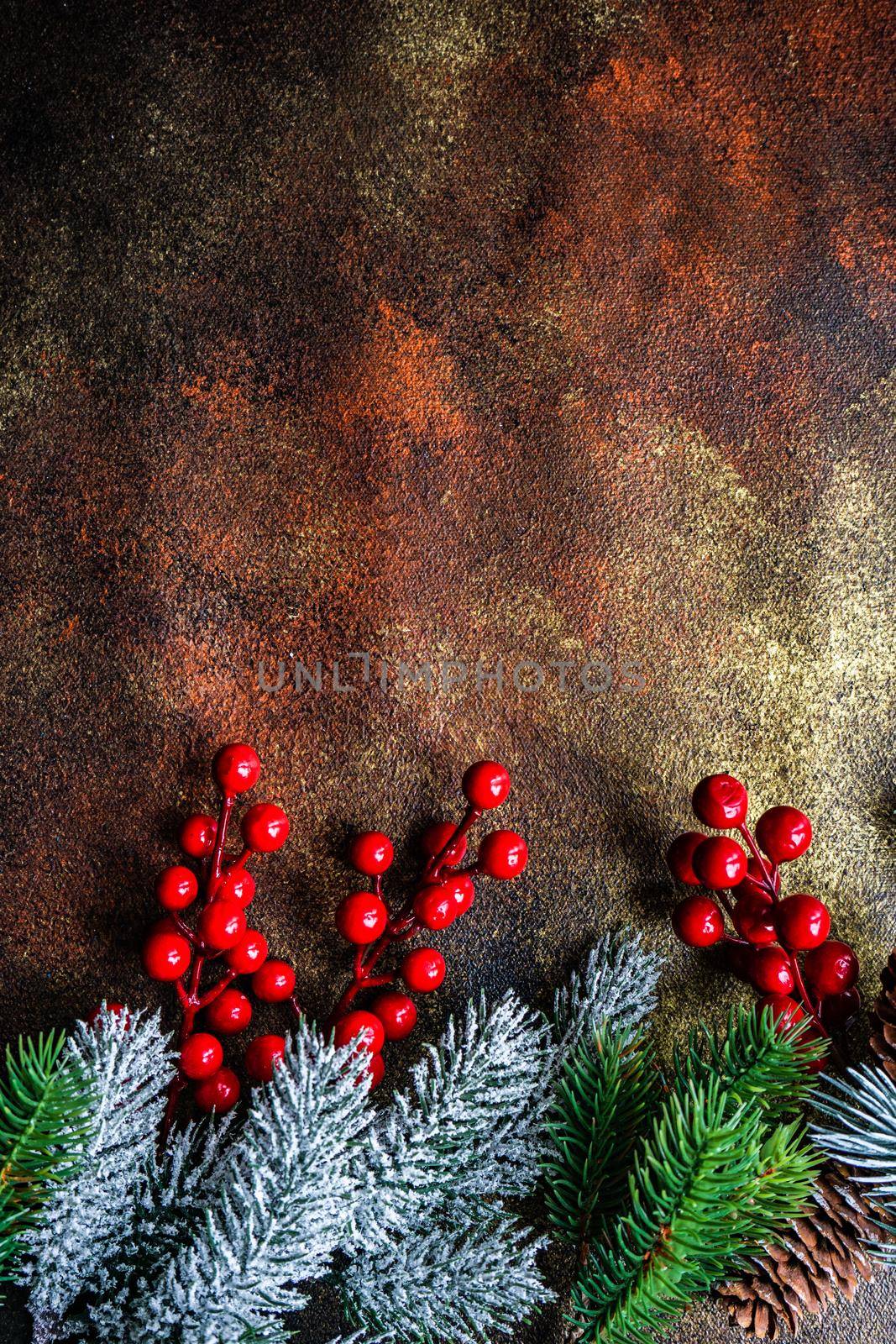 Christmas card concept with frame made with green fir branches, red decoration balls and berries on concrete background