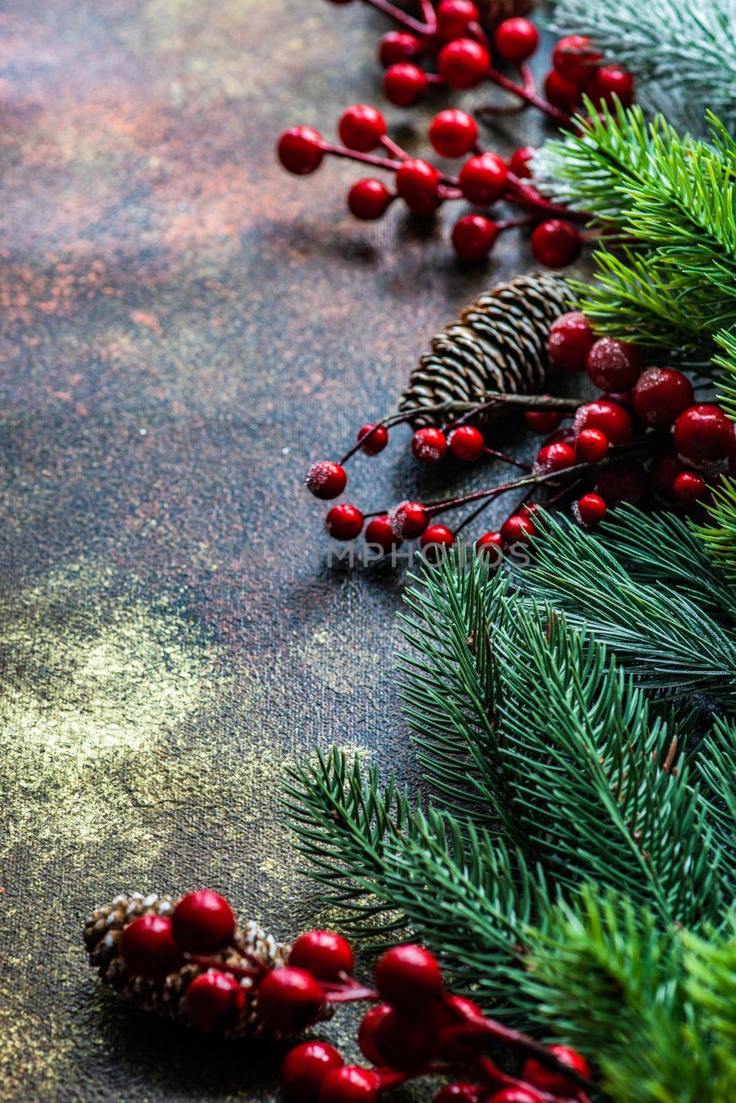 Christmas card concept with frame made with green fir branches, red decoration balls and berries on concrete background