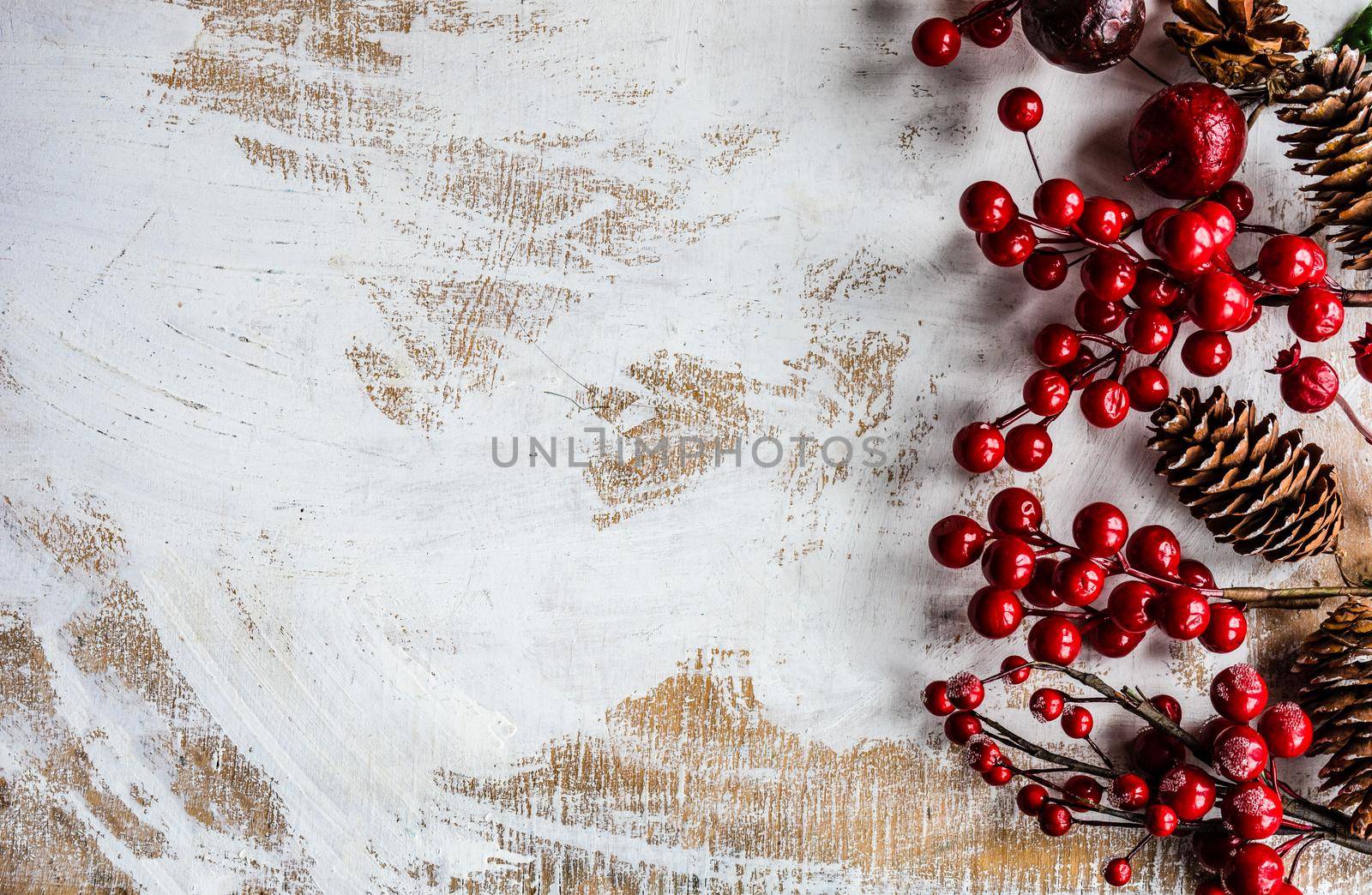 Christmas card concept with frame made with green fir branches, red decoration balls and berries on concrete background